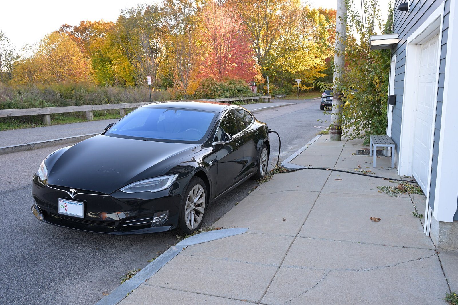 A white electric car charging in the driveway of a modern home