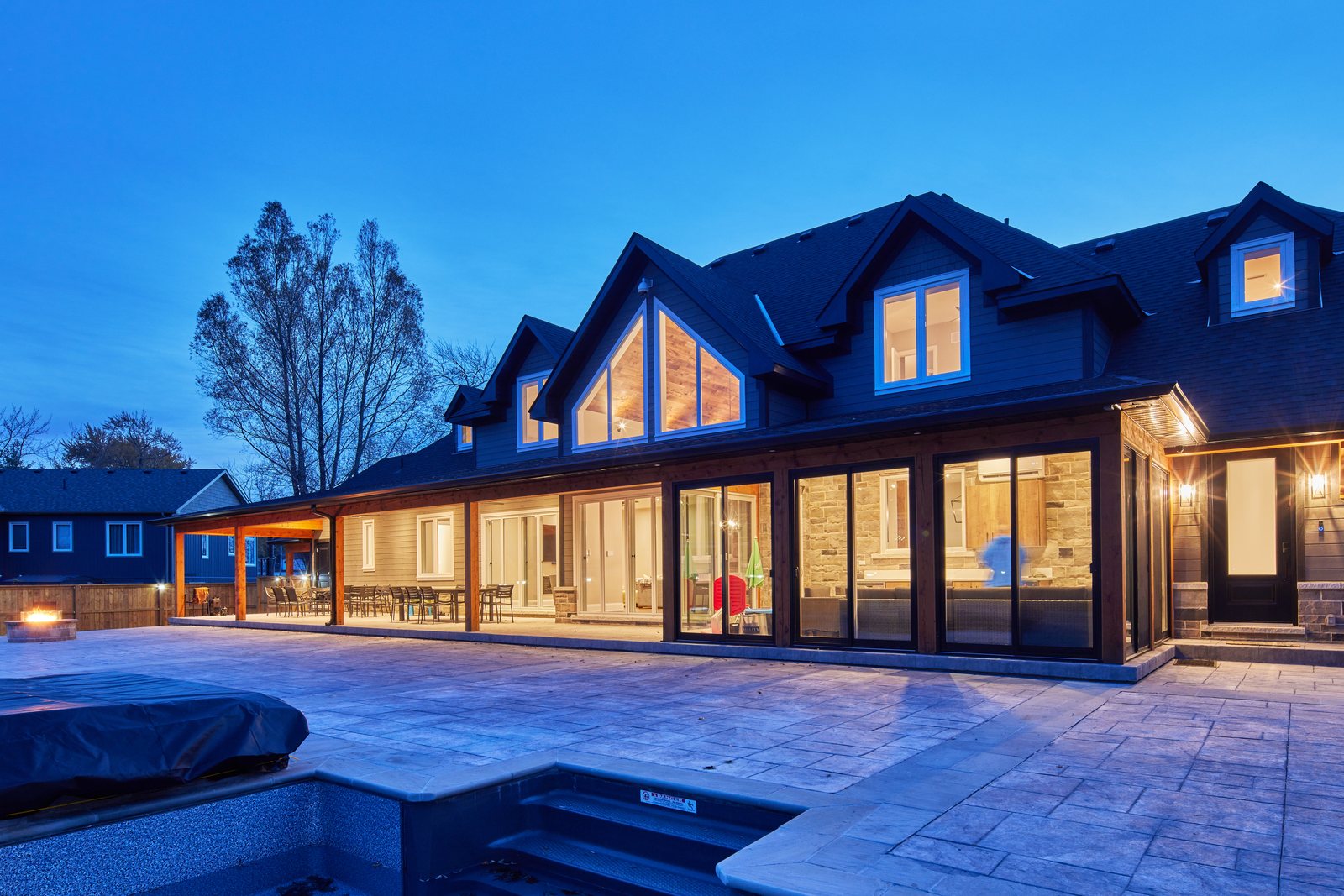 A large custom home lit from inside at dusk, the neighbors dark